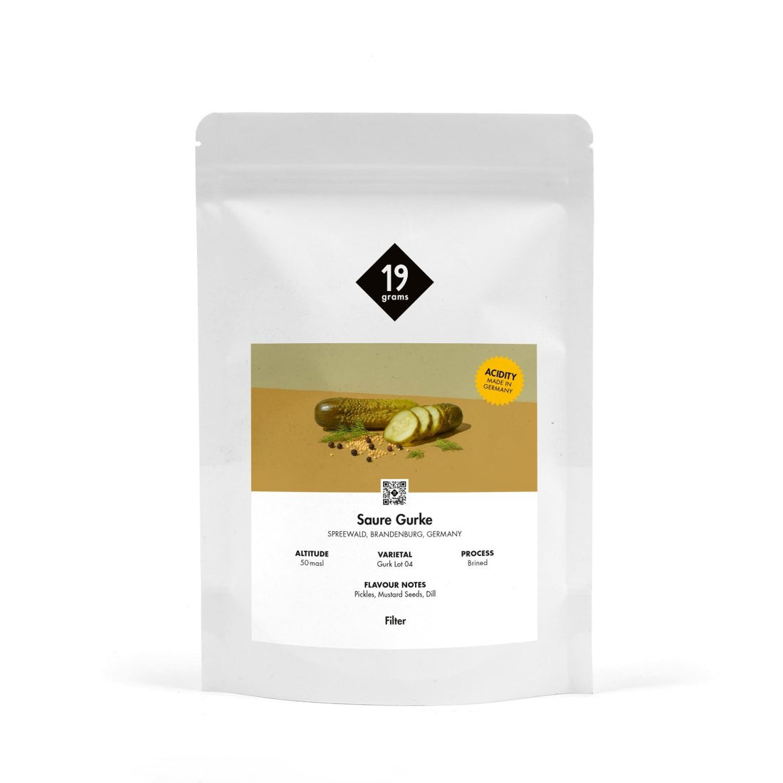 Produktmockup der 19grams Kaffeeverpackung „Saure Gurke" mit olivgrüner Banderole und Gurkenmotiv auf weißem Hintergrund