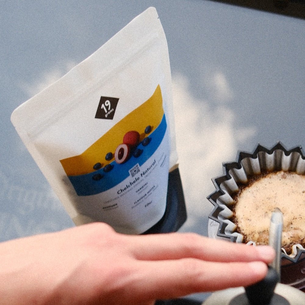 19grams Kaffeeverpackung Chelchele Natural Filter aus Äthiopien – Hand hält die Tüte neben einem Kaffeefilter