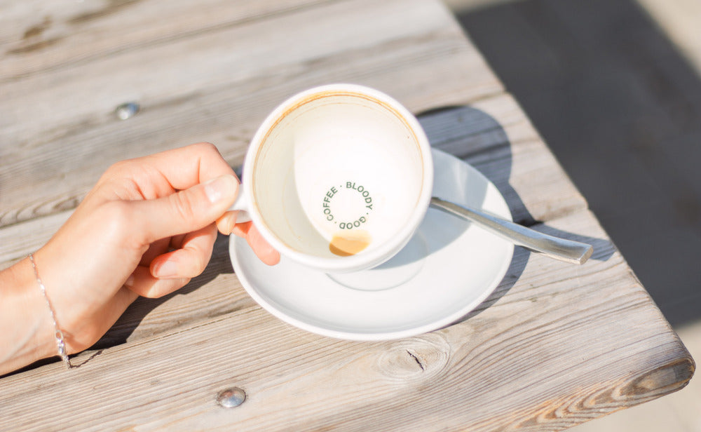 Leere Tasse 19grams Milchkaffee mit Bloody Good Coffee auf dem Tassenboden