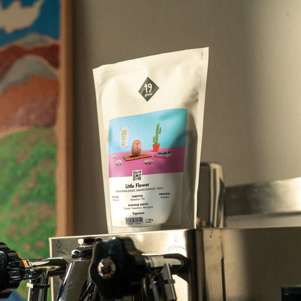 19grams Kaffeeverpackung „Little Flower" mit bunter Wüsten-Illustration auf einer Espressomaschine
