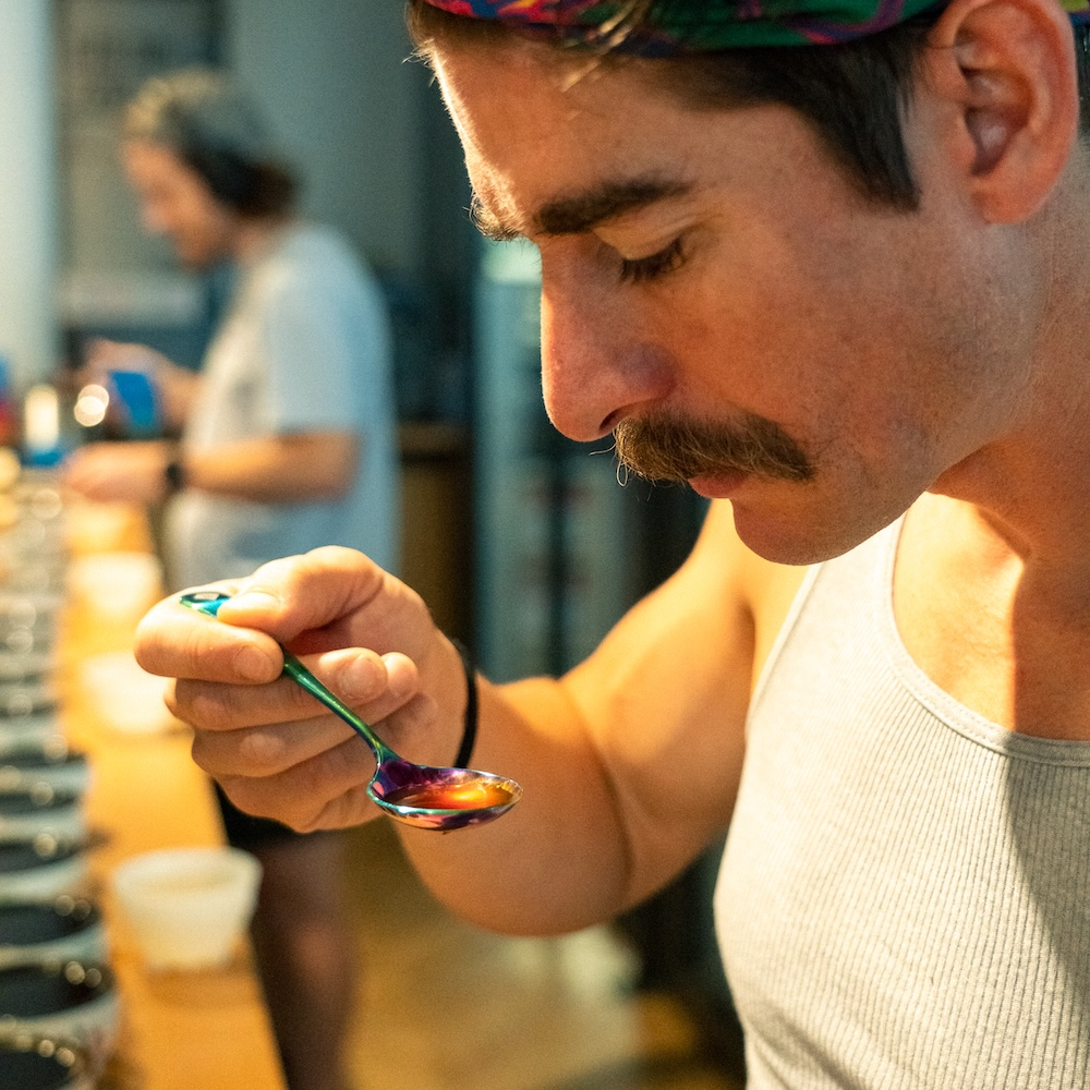 Barista beim konzentrierten Kaffee-Cupping mit 19grams Bloody Good Rainbow Cupping Löffel – Sensorik-Verkostung in der Rösterei