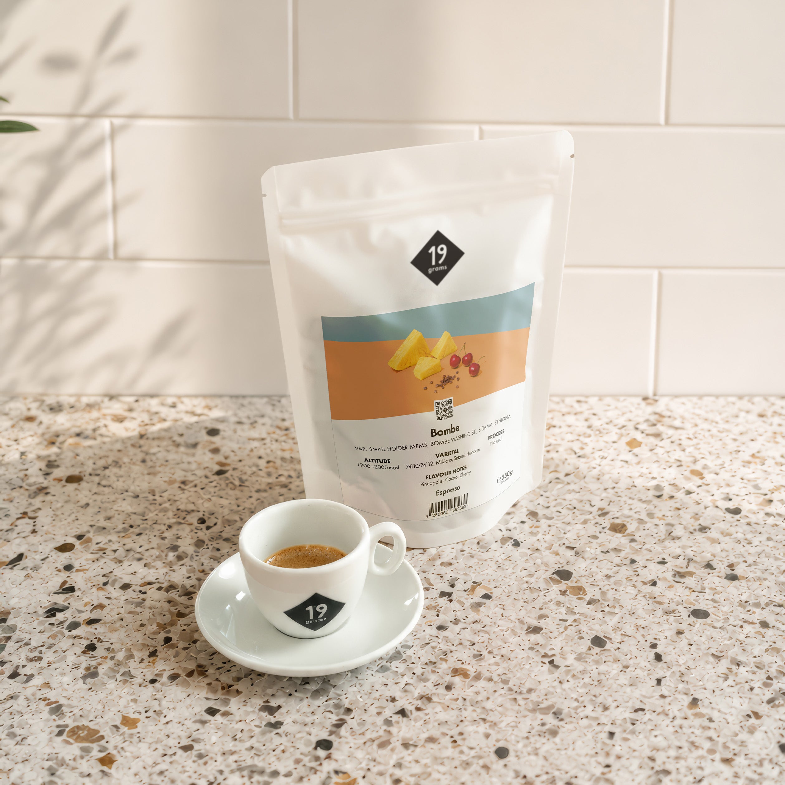 19grams Bombe Specialty Coffee Espresso – Kaffeebeutel neben frisch zubereitetem Espresso auf Terrazzo-Arbeitsplatte, Kaffeerösterei Berlin