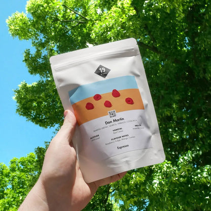 19grams Don Martin Espresso aus Berlin in der Hand präsentiert mit Baumkrone im Hintergrund