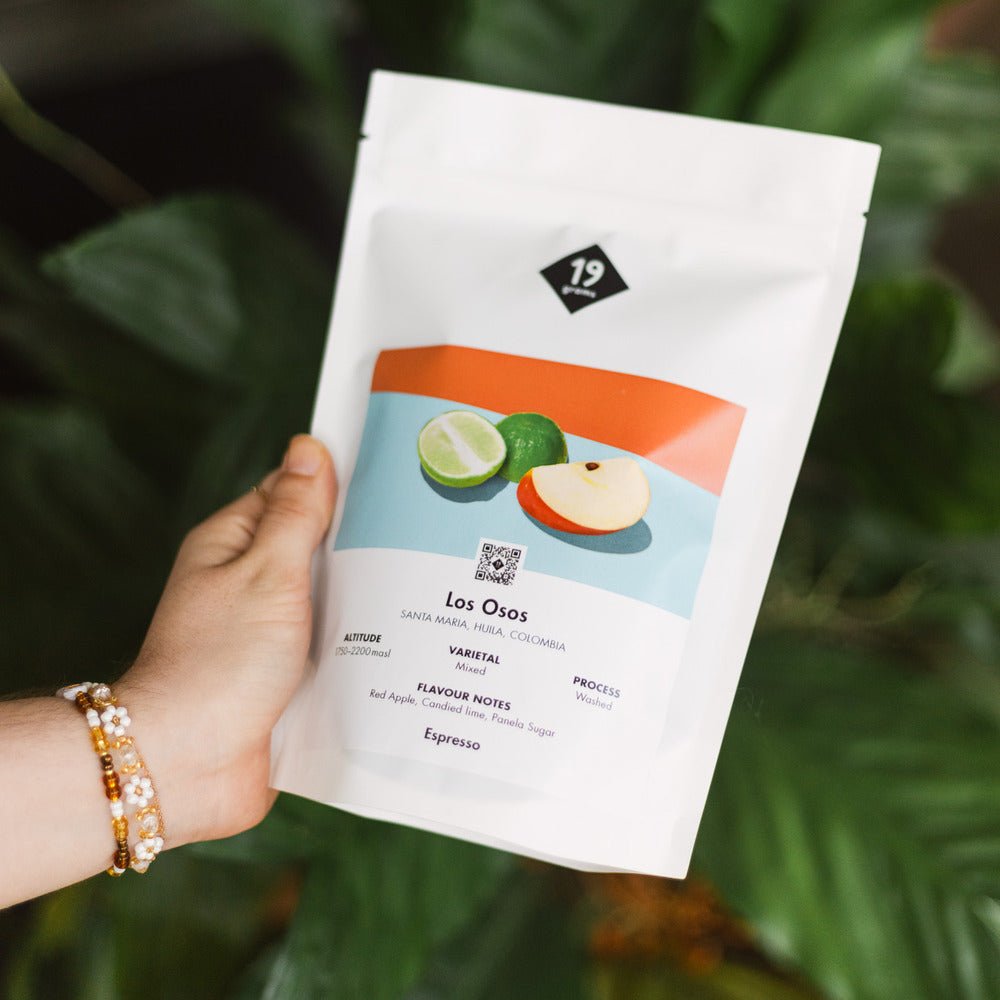 19grams Los Osos Espresso Kaffeebeutel in der Hand vor Blätterhintergrund – Huila Kolumbien Specialty Coffee Espresso von 19grams Berlin