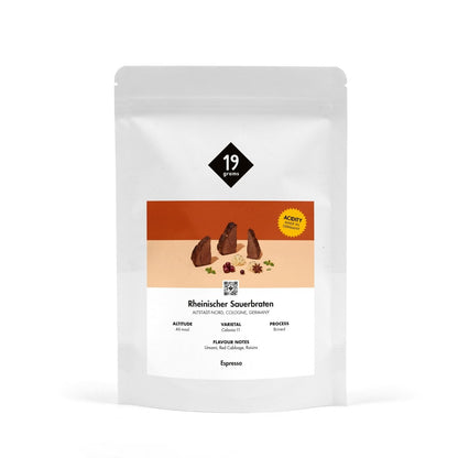 Produktmockup der 19grams Kaffeeverpackung „Rheinischer Sauerbraten" mit orangefarbener Banderole auf weißem Hintergrund