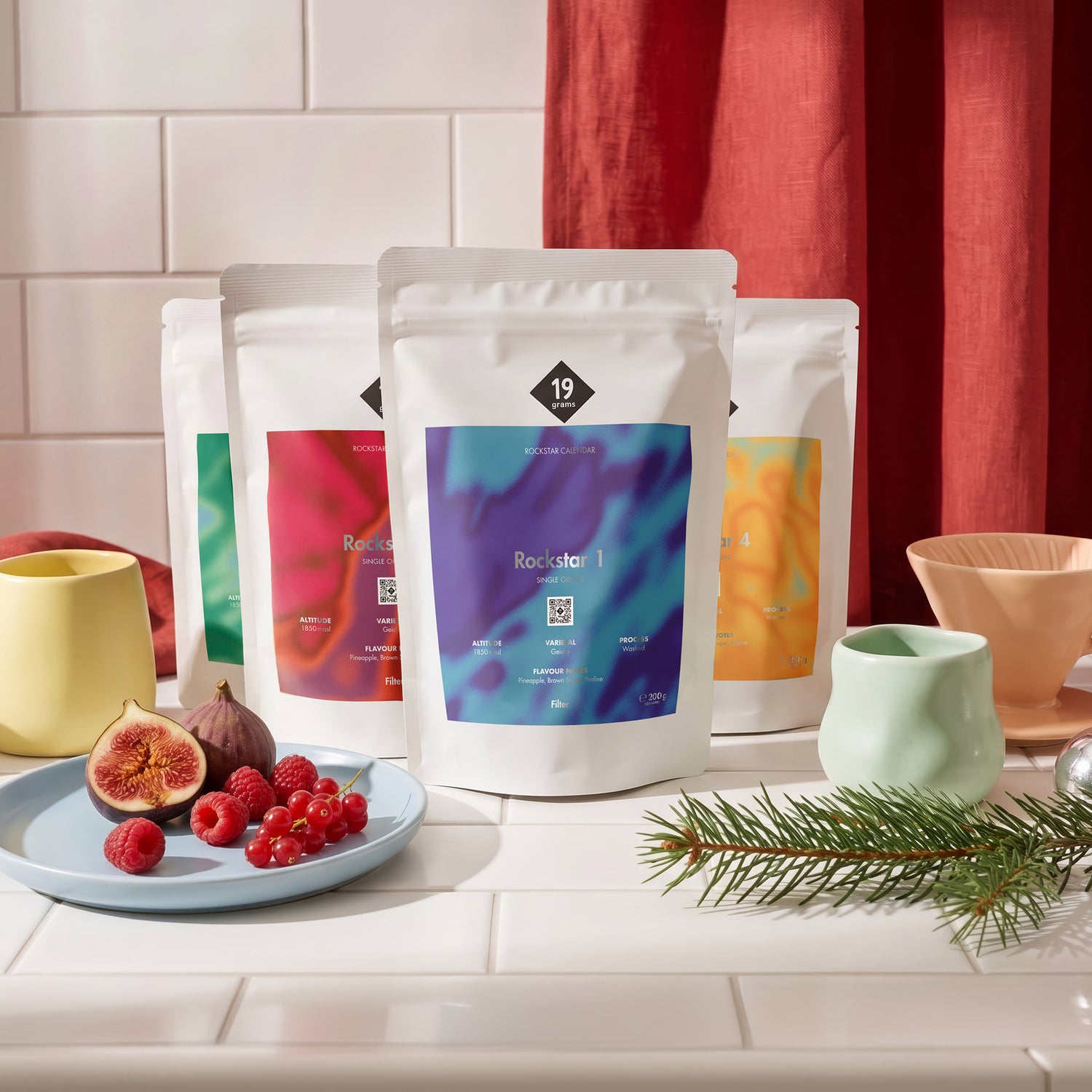 19grams Rockstar Calendar Specialty Coffee Moodbild – Bunte 19grams Kaffeebeutel mit Handfilter, Tasse, Feigen und Beeren auf Küchenfliesen, Kaffeerösterei Berlin