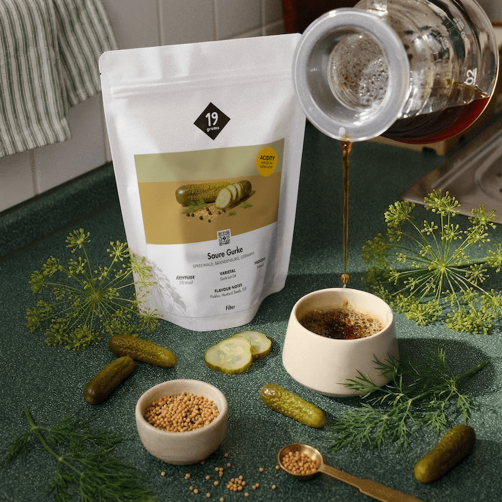 19grams Kaffeeverpackung „Saure Gurke" mit frischen Gurken, Dill, Senförnern und eingegorener Brühe als Produktfoto-Flatlay