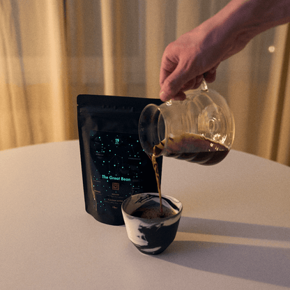 19grams „The Great Bean" – Filterkaffee aus Glaskanne in Keramiktasse, dunkle Verpackung mit Sternbild