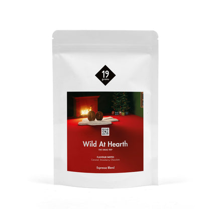 19grams Wild At Hearth Specialty Coffee Espresso Blend – Kaffeebeutel Produktmockup mit Kamin und Weihnachtsbaum-Motiv, The Xmas Trip Edition, Kaffeerösterei Berlin